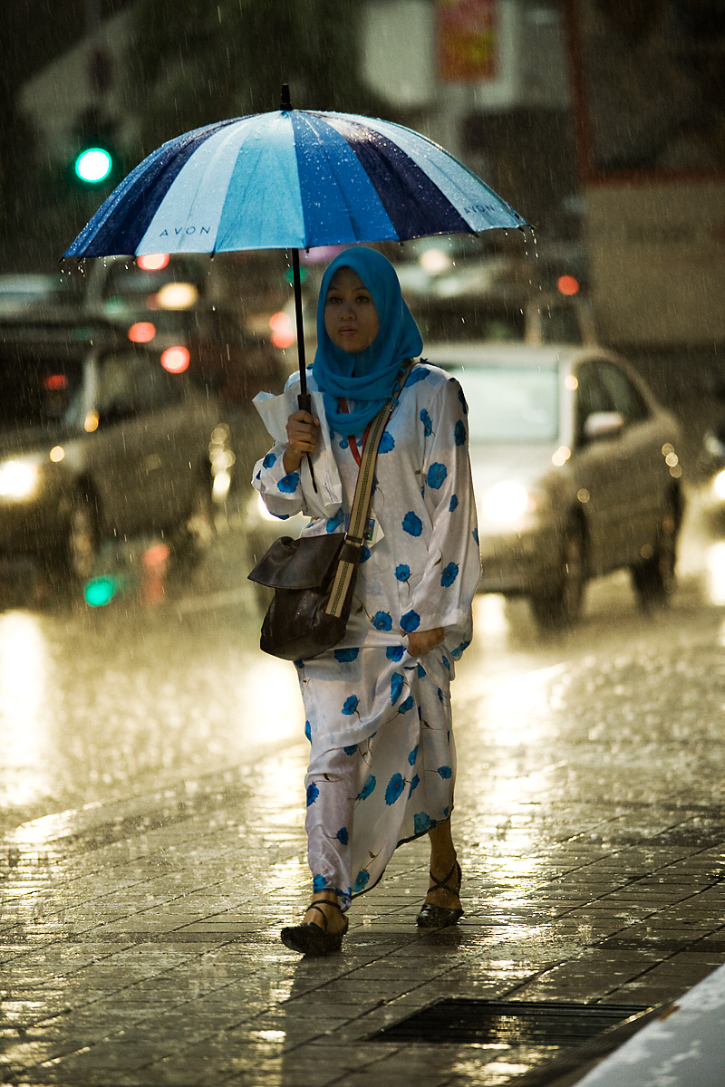 Rainy Day Blues (& Pinks) - A Muslim woman remains dry during a typical ...