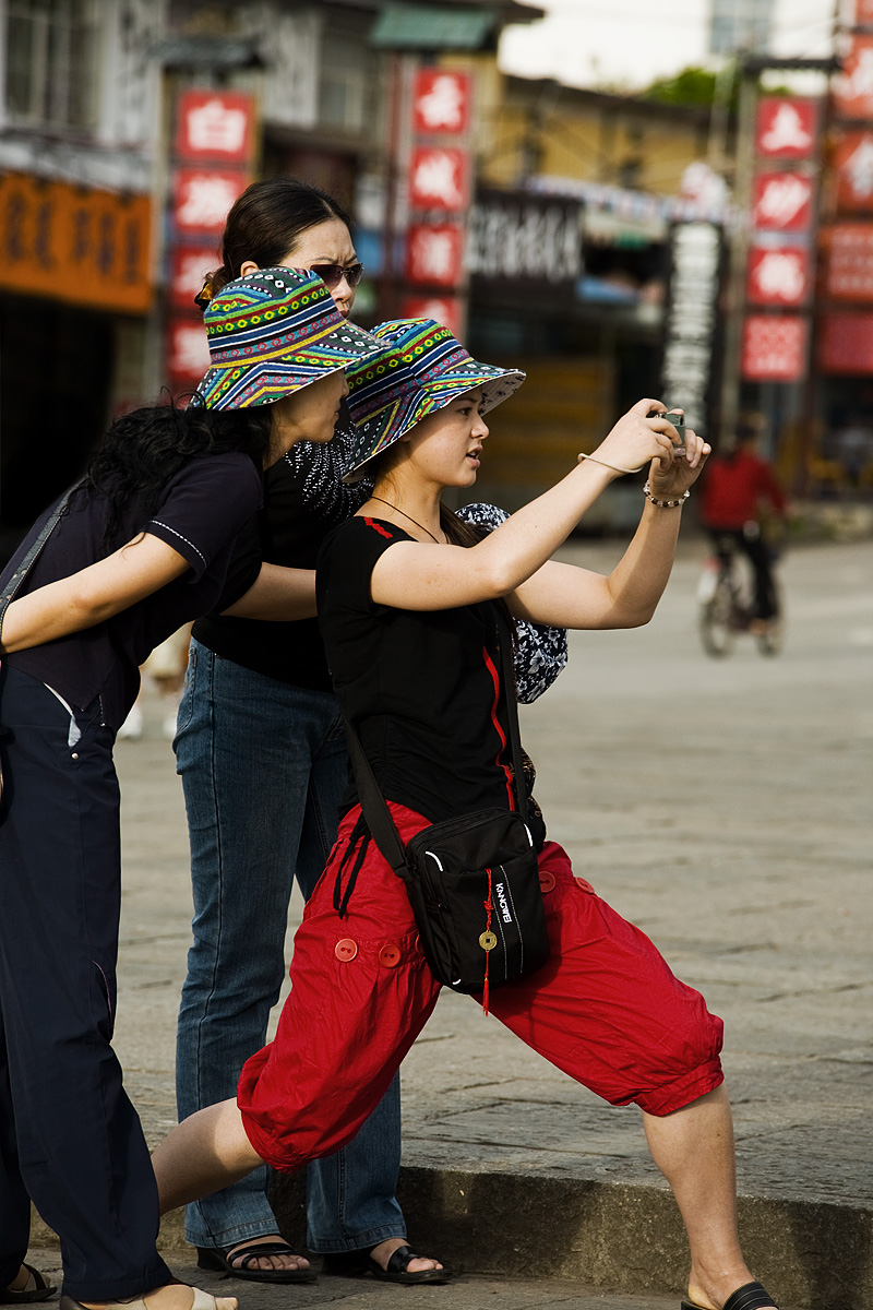 A Chinese woman strikes an atypical picture snapping position. - Dali, Yunnan, China - Daily Travel Photos