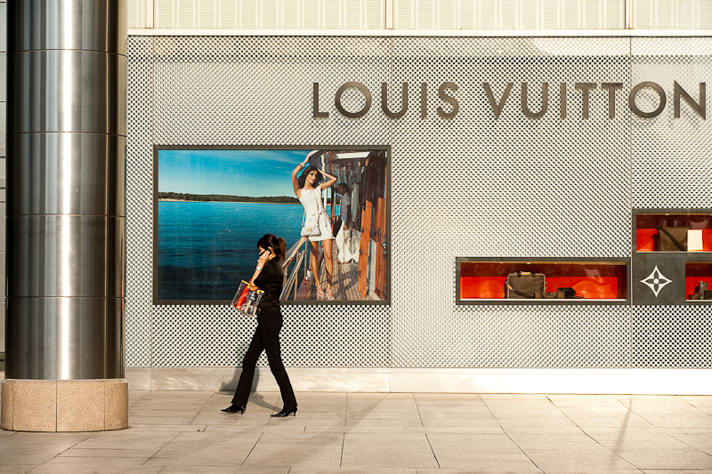 An ethnic Chinese-Malaysian woman walks in front of a Louis Vuitton store. - Kuala Lumpur, Malaysia - Daily Travel Photos
