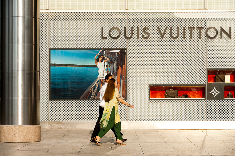 A pair of ethnic Indian-Malaysians walk in front of a Louis Vuitton store. - Kuala Lumpur, Malaysia - Daily Travel Photos