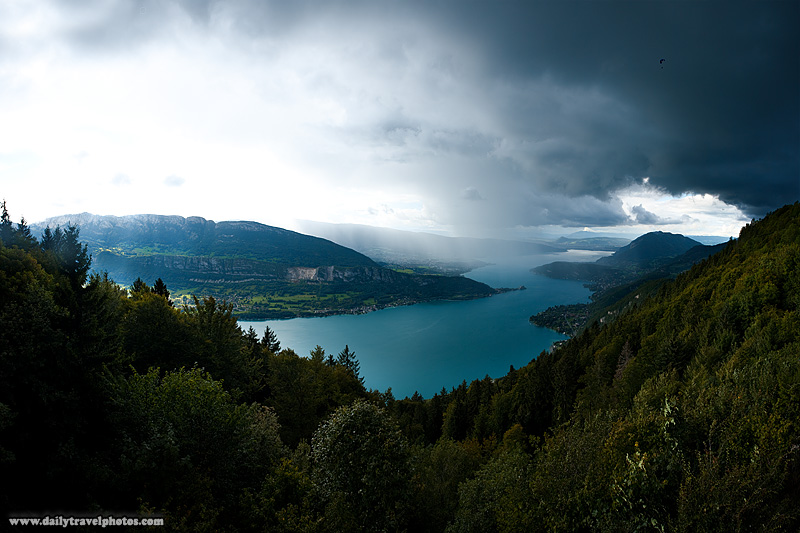 A paraglider braves storm clouds for a fly in the sky over Annecy Lake - Col de La Forclaz, Haute-Savoie, France - Daily Travel Photos