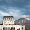 Rich Retreat Photo: A side-view of the Hotel Imperial Palace, a lakeside casino, with the mountains of Annecy, France in the background.